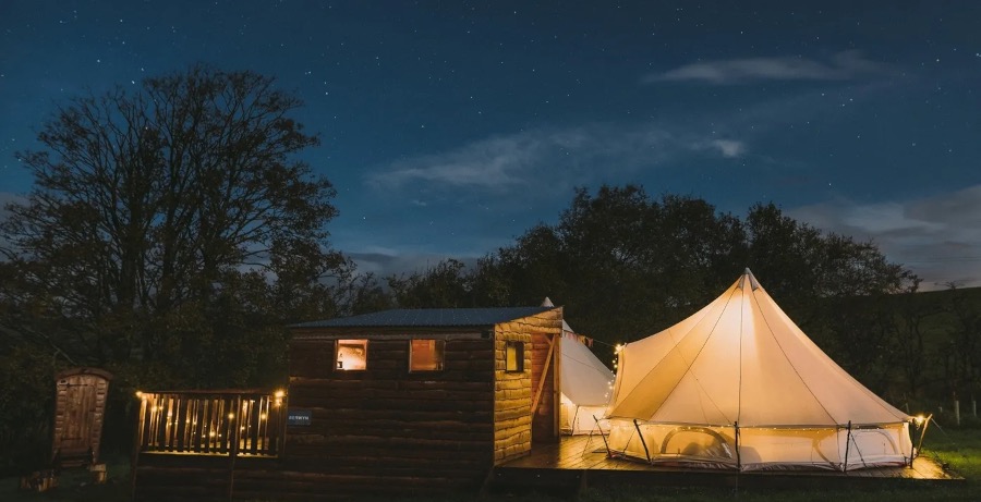A bell tent glowing at night at The Forge